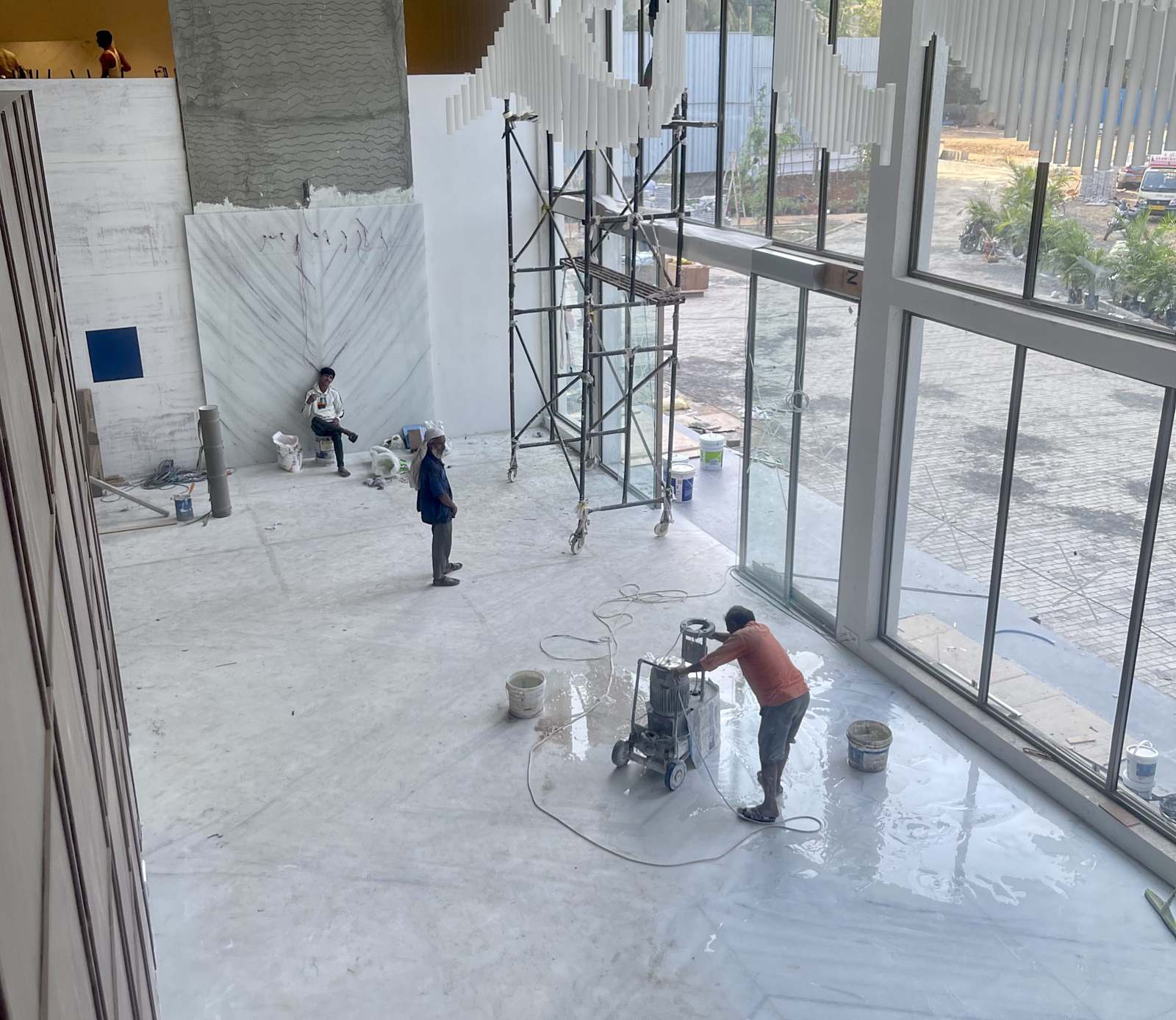 Marble floor being installed and polished inside a glass-fronted lobby