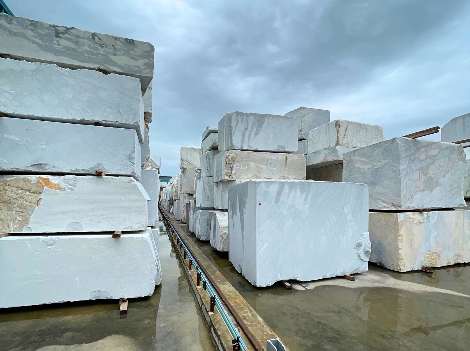 Rows of cut stone blocks on a wet stone yard floor